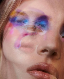 Close-up beauty portrait of a woman with colorful abstract eye makeup and layered holographic light effects.