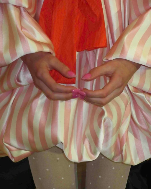 Close-up shot of a person wearing a striped dress with an orange sash, paired with polka dot tights, showcasing a fashion-forward look.