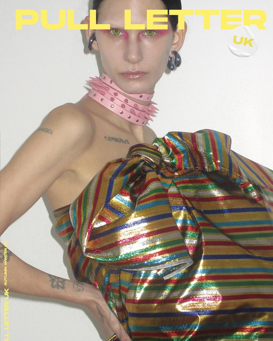 Avant-garde fashion magazine cover featuring a fashion model wearing a pink spiked collar and a striped metallic textile garment.