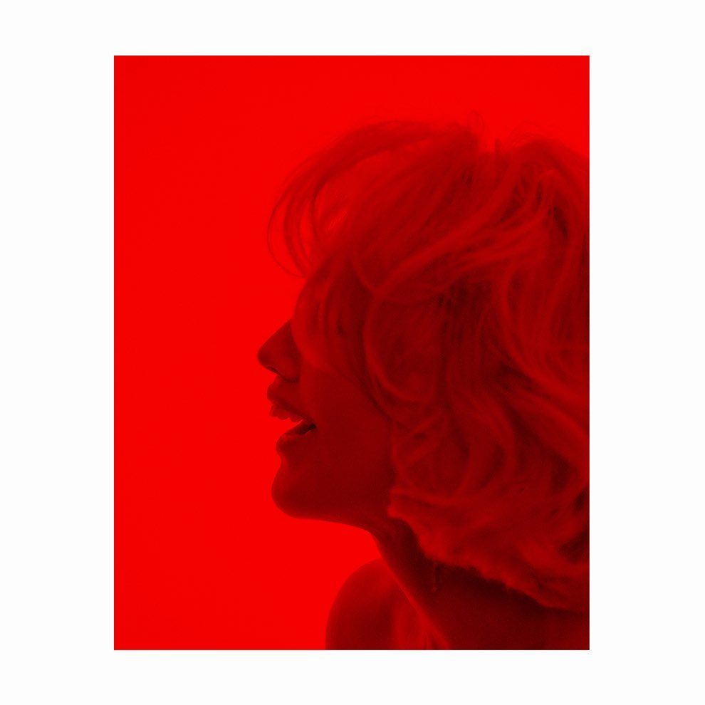 Profile of a woman with curly hair shown in silhouette. The image is rendered entirely in shades of red, from light to dark.
