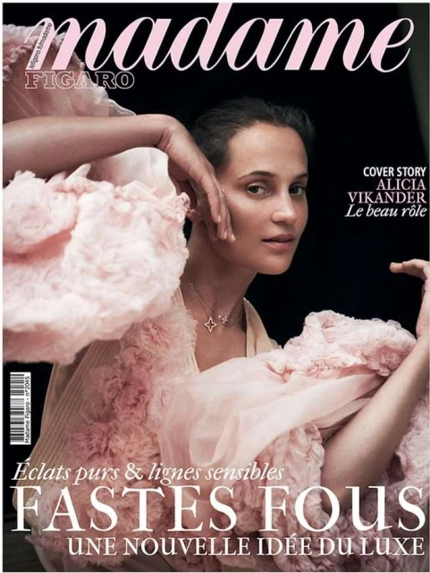 Alicia Vikander on Madame Figaro cover in flowing pink dress. Close-up portrait, star necklace, hands near face, and elegant magazine design.