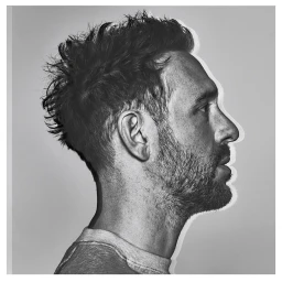 Monochrome profile portrait of a bearded man in a crew neck t-shirt against a light grey background