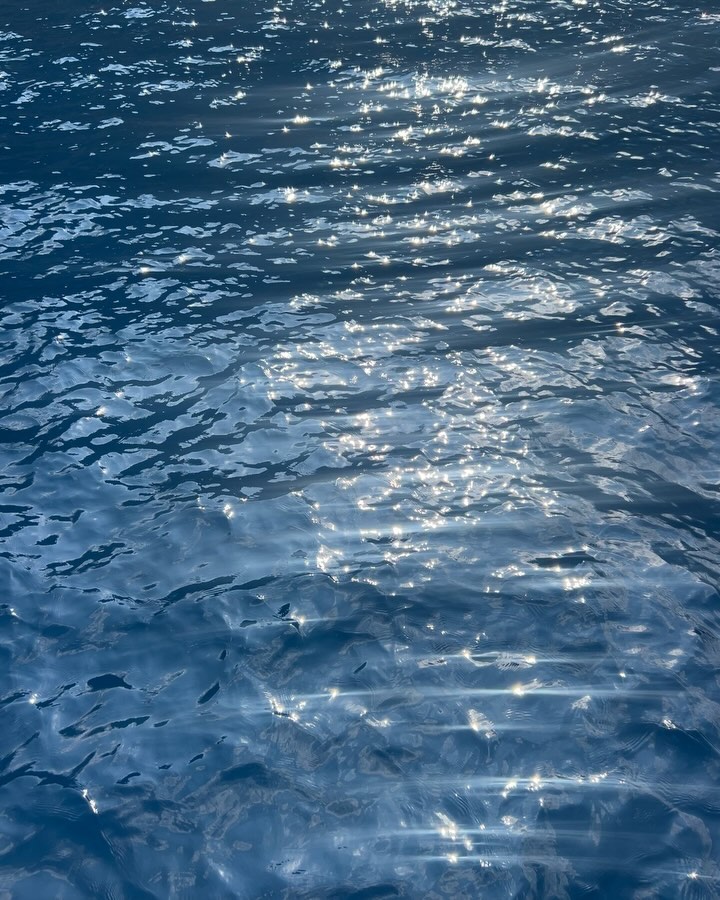 Sparkling turquoise water with gentle ripples and sun reflections creating a dynamic, textured surface, reminiscent of a serene ocean scene.