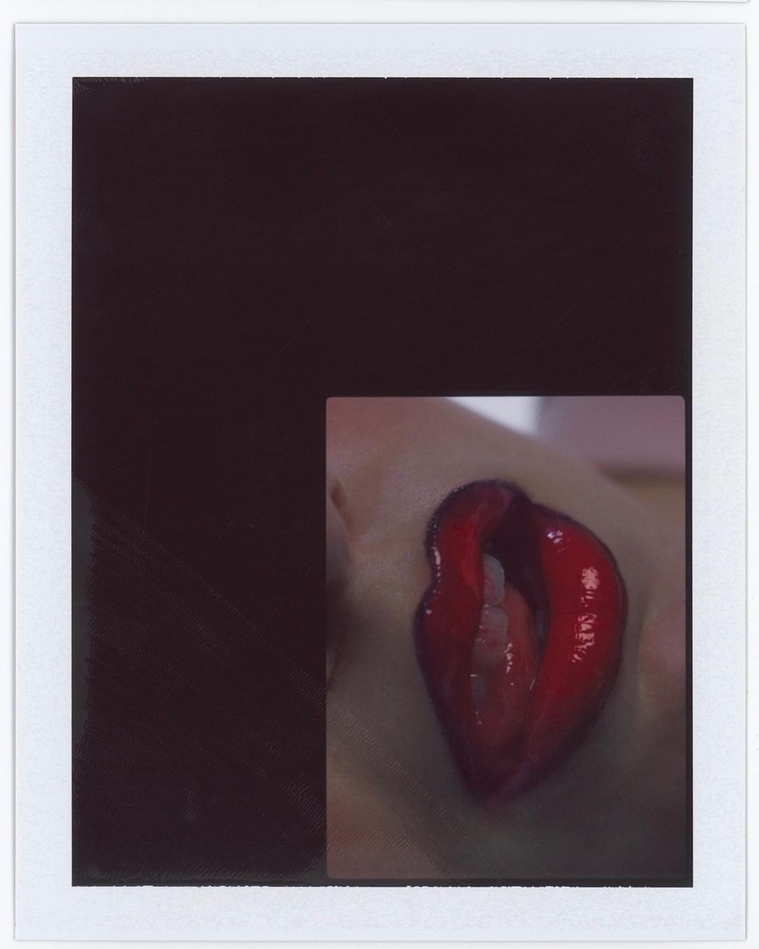 Close-up photograph shows an eye with a red eyelid, presented as an isolated subject within a dark Polaroid frame.