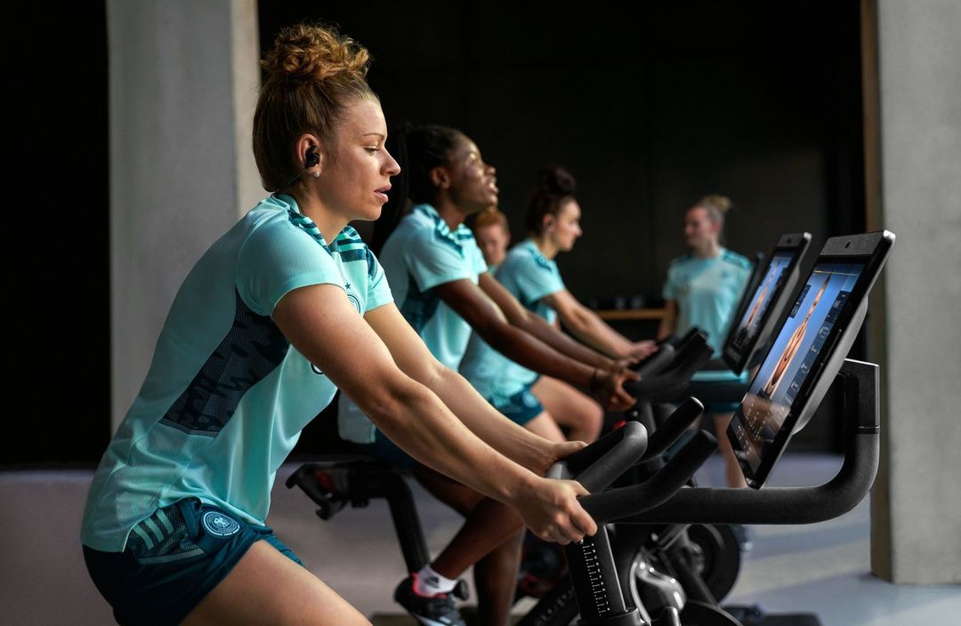 Group of diverse women in sports clothing are riding stationary exercise bikes in a fitness studio during a workout session.