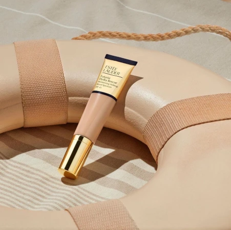 Estee Lauder Futurist Hydra Rescue moisturizing makeup SPF 45 tube rests on a beige life preserver against a striped fabric backdrop.