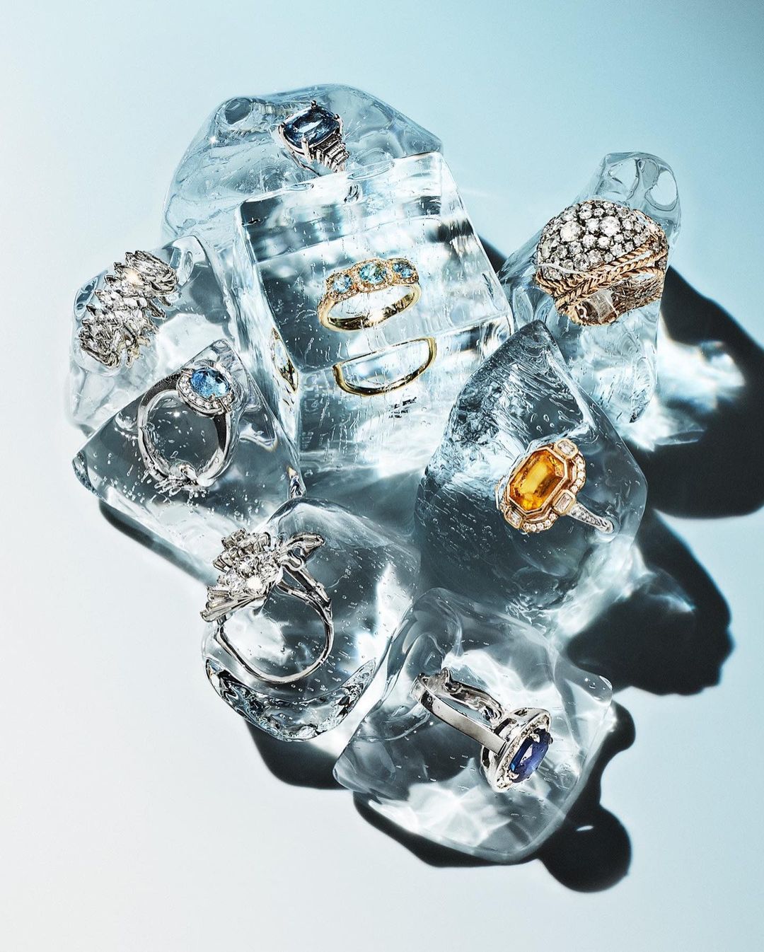 Elegant rings with gemstones displayed on ice cubes, creating a visually appealing and luxurious still-life jewelry composition.