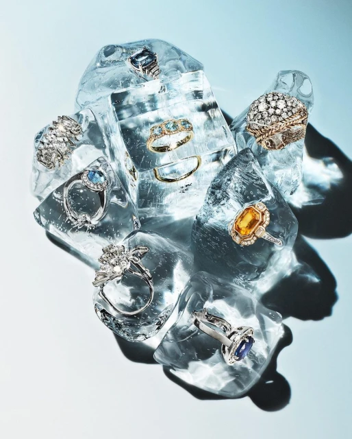 Elegant rings with gemstones displayed on ice cubes, creating a visually appealing and luxurious still-life jewelry composition.