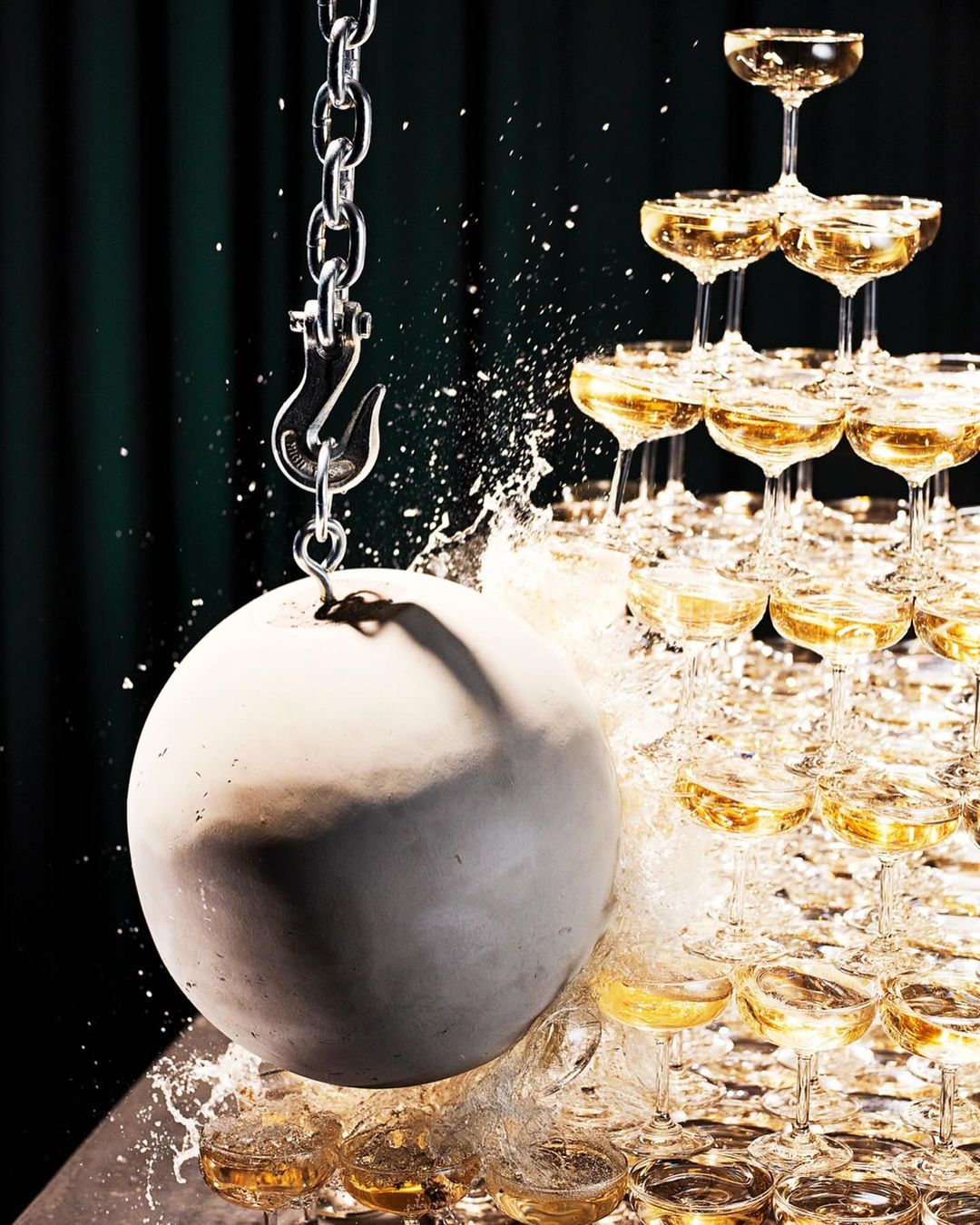 Champagne tower is destroyed by a wrecking ball. The champagne spills out of the glasses as the steel ball crashes into them.