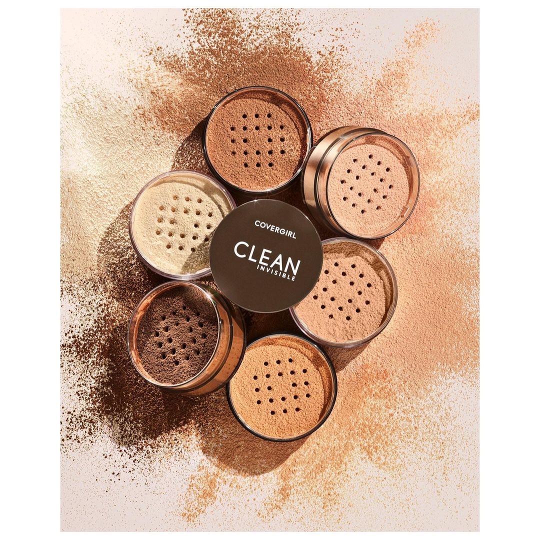 Close-up product shot of Covergirl Clean Invisible loose powder makeup in multiple containers, arranged on a background with powder.
