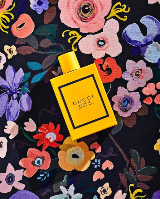 Yellow Gucci Bloom perfume bottle on a floral patterned surface, product shot, beauty, fragrance, floral design, luxury aesthetic.