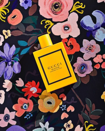Yellow Gucci Bloom perfume bottle on a floral patterned surface, product shot, beauty, fragrance, floral design, luxury aesthetic.