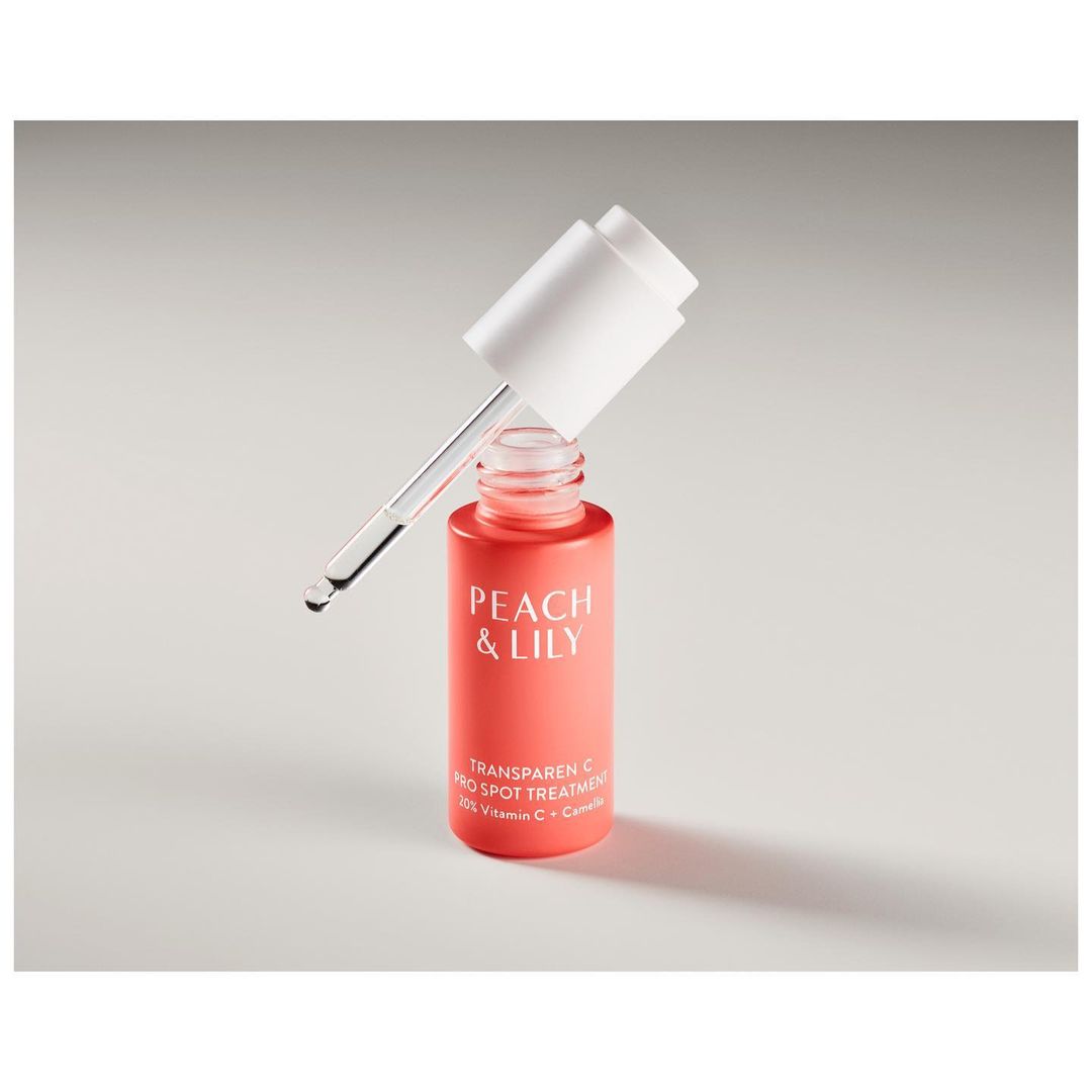 Peach & Lily transparent C dark spot treatment serum bottle and dropper against a neutral background in a product shot.