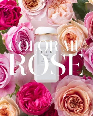 Aerin perfume bottle surrounded by a lush arrangement of blooming pink and peach garden roses