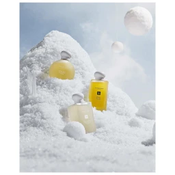 Three perfume bottles resting in a snow mound under a pale blue sky with hanging snowballs by Jarren Vink