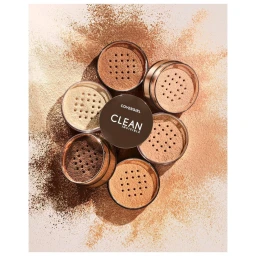 Top-down view of six round loose powder makeup containers arranged in a circle with loose powder splattered around them.