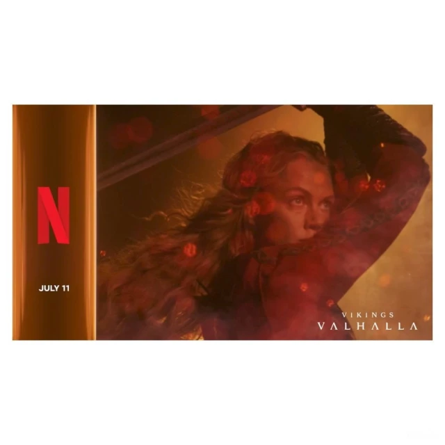 Adult woman with sword in Viking costume with blond hair. Netflix advertisement for Vikings Valhalla, set in muted yellow, red tones.