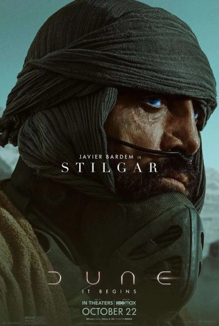 Movie poster of Javier Bardem as Stilgar in Dune: a close-up of a man in a head covering and mask with blue eyes, set against a tan background.