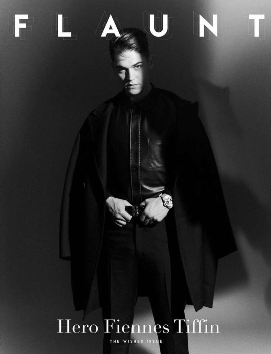 Black-and-white portrait of Hero Fiennes Tiffin on a magazine cover, wearing dark clothing and a watch, with the magazine's title visible.
