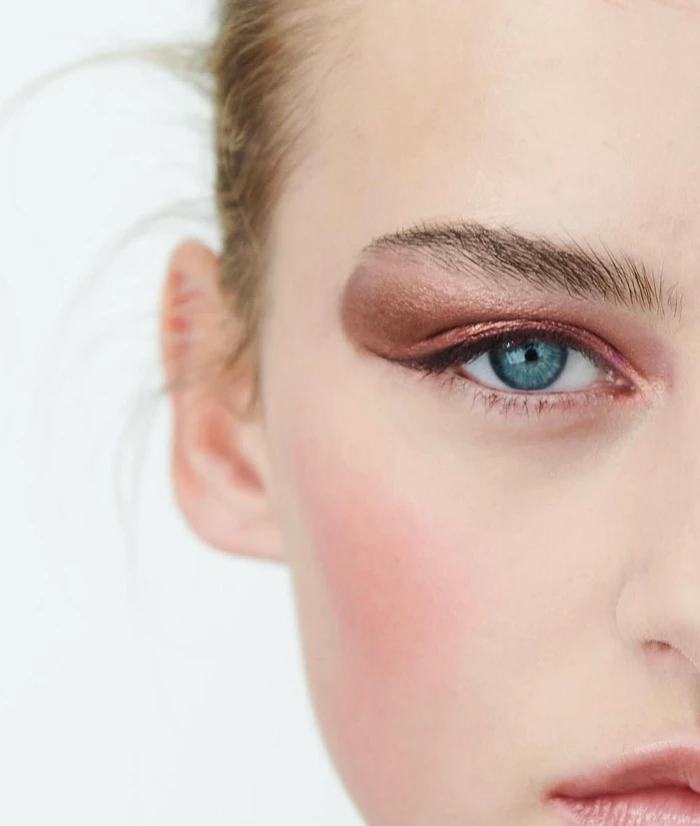 Close-up portrait of a woman with striking blue eyes and bronze eyeshadow, shot by Jason Hetherington.