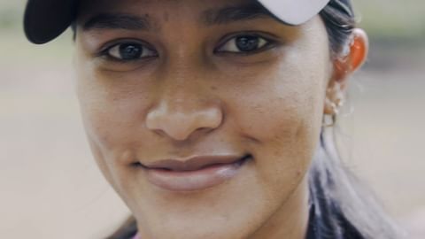 Close-up portrait of a smiling young woman wearing a cap looking directly at the camera