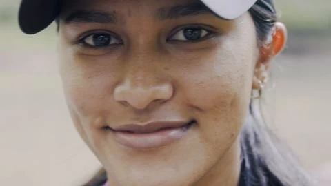 Close-up portrait of a smiling young woman wearing a cap looking directly at the camera