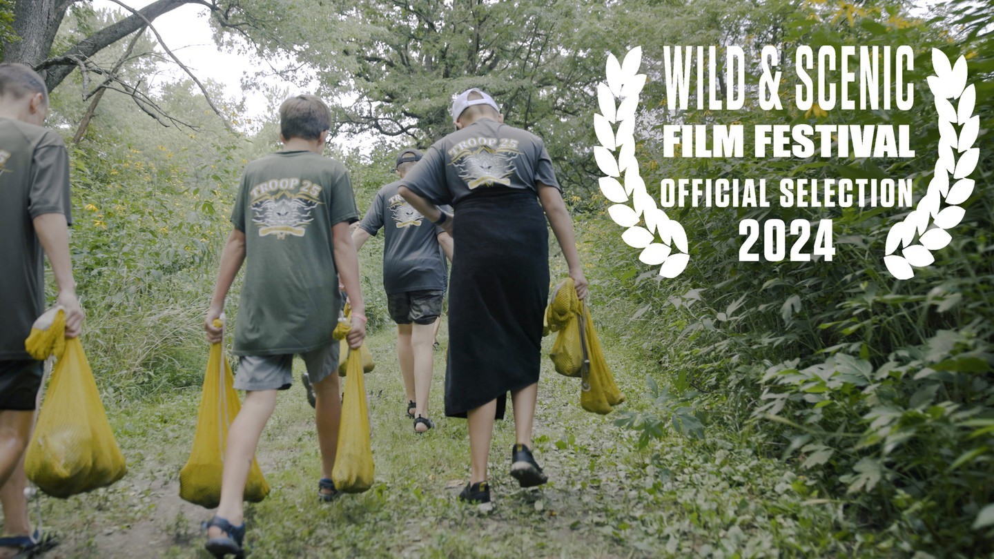 Group of people hikes on trail carrying yellow bags, outdoor, daytime. Wild & Scenic Film Festival Official Selection 2024 award graphic.
