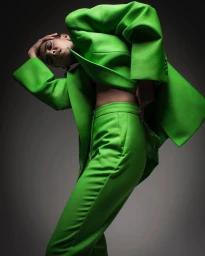 Model in vibrant green suit posing dramatically against a neutral grey studio background by photographer Jason Madara