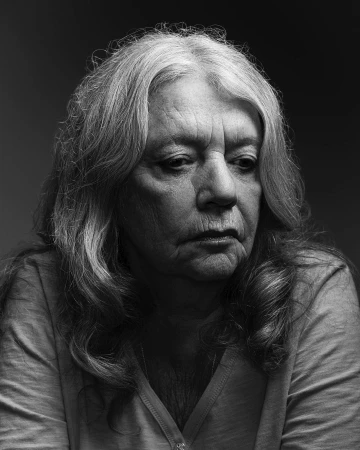 Portrait of an elderly woman with long wavy hair and serious expression photographed by Jason Madara