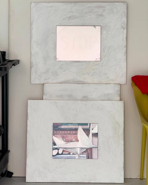 Two framed art pieces, one with abstract white shapes on a dark background and the other with a blurry, blank image on a gray backdrop.