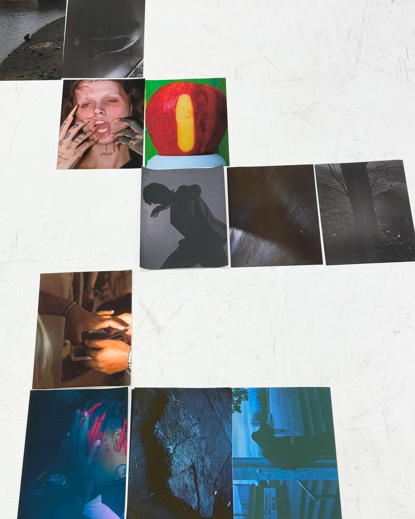 A collage of printed photographic images with subjects including a person, fruit, silhouette, landscape, and partial figures on a white surface.