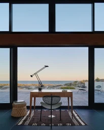 Wooden desk and modern chair facing large windows overlooking ocean view by photographer Jason Schmidt