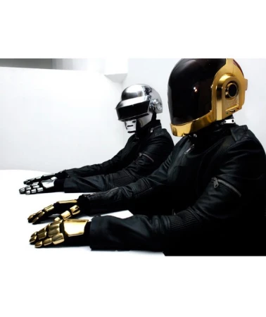 Two people wearing Daft Punk helmets and black jackets sitting at a white table, showcasing music, celebrity and entertainment themes.