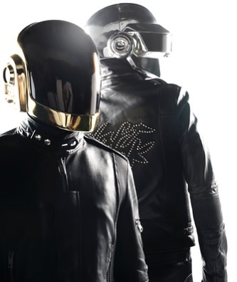 Two musicians wear Daft Punk-style helmets and black leather jackets, standing in a brightly lit, neutral setting.