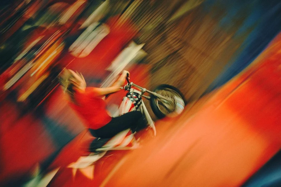 Adult on a motorbike with long exposure and motion blur against a red background in an abstract outdoor shot. 