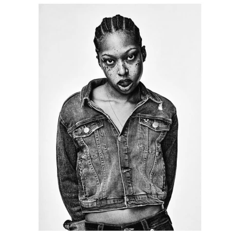 Monochrome portrait of a Black woman wearing a denim jacket with braided hair against a plain white background