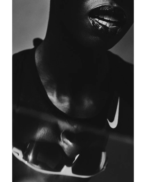 Close-up portrait of an African-descent woman with dark skin and glossy lips wearing a sports shirt with a Nike logo, showcasing athletic style.