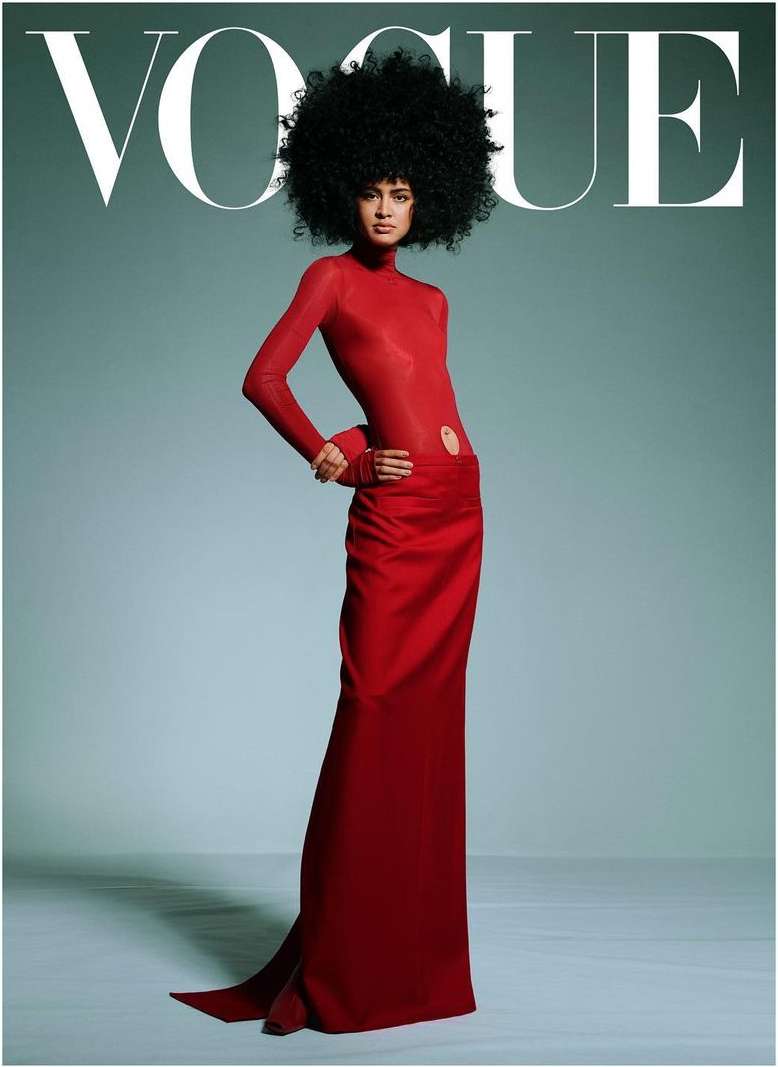 Vogue cover featuring a woman with dark curly hair, red top and long red skirt posing against a light blue background.