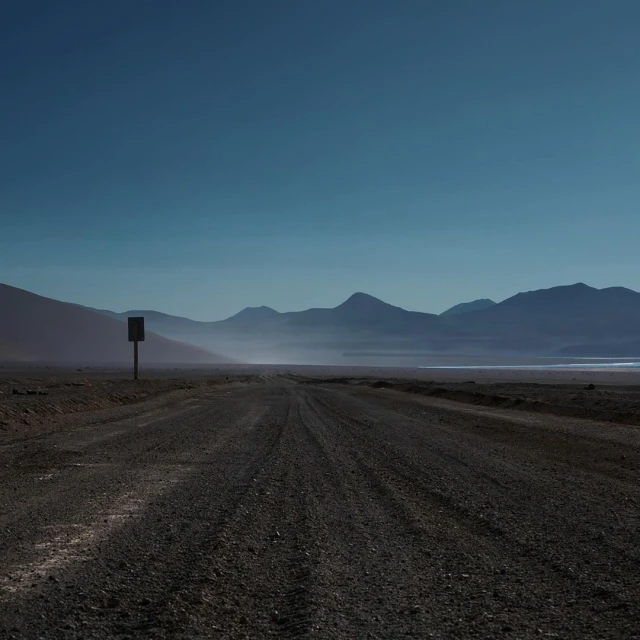 Distant mountains and a vast, empty landscape are visible under a clear blue sky, creating a sense of solitude and open space.