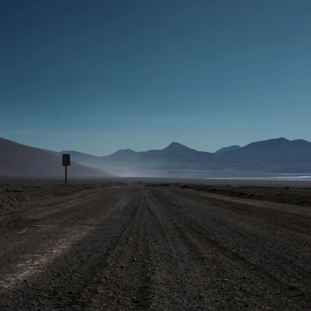 Distant mountains and a vast, empty landscape are visible under a clear blue sky, creating a sense of solitude and open space.