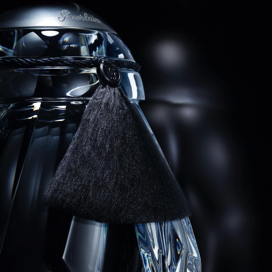 Crystal Guerlain perfume bottle with a black tassel on a dark background, product shot for beauty and fashion industries.