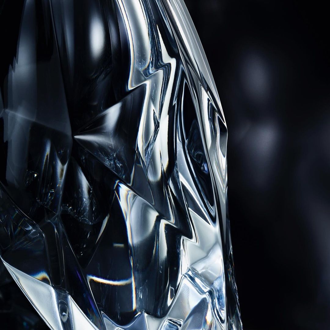Close-up studio shot of a cut crystal object reflecting light against a dark background, showcasing its intricate geometric design.