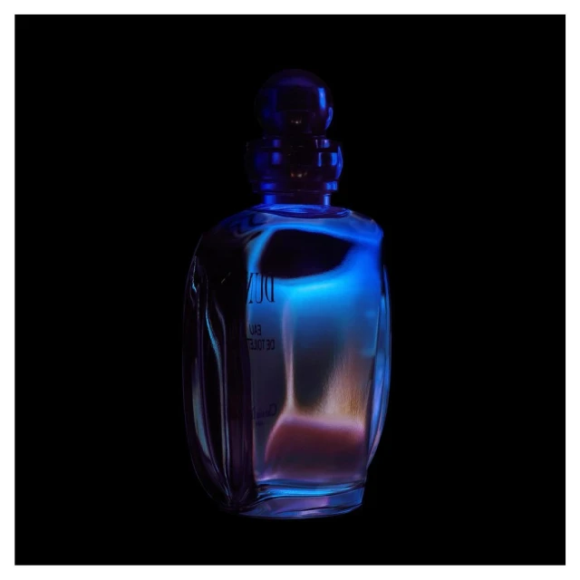 Translucent perfume bottle stands out with blue and orange tones against a stark black backdrop, highlighting its sleek design.