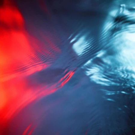 Abstract ripples of water illuminated by contrasting red and blue light creating dynamic fluid texture.