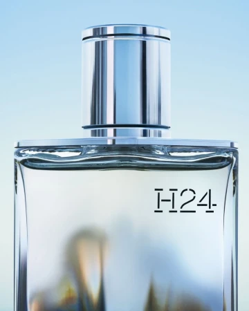 Elegant studio shot of H24 fragrance bottle with silver cap against a soft blue background, showcasing its design and minimalist aesthetic.