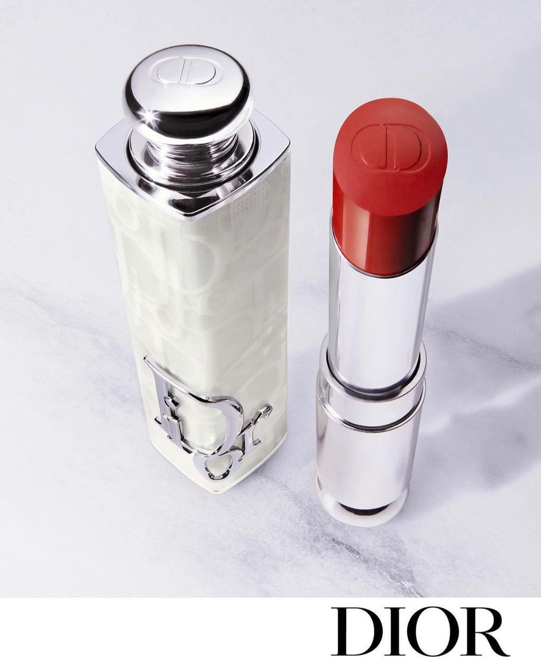 Elevated shot of Dior lipstick and perfume bottle set against a marble backdrop, showcasing luxury beauty and minimalist elegance.