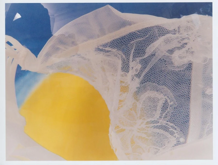 Abstract art featuring yellow and blue hues alongside a textured white textile, creating a layered and visually intriguing composition.