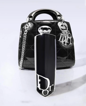 Elegant composition featuring a black Lady Dior handbag and a Dior perfume bottle, set against a clean, bright background. 