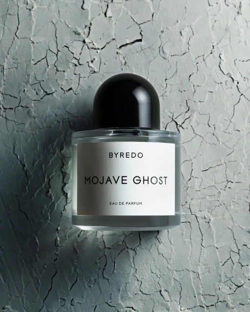 Byredo Mojave Ghost eau de parfum bottle on textured gray surface. Product shot of fragrance with sleek design and minimal label.