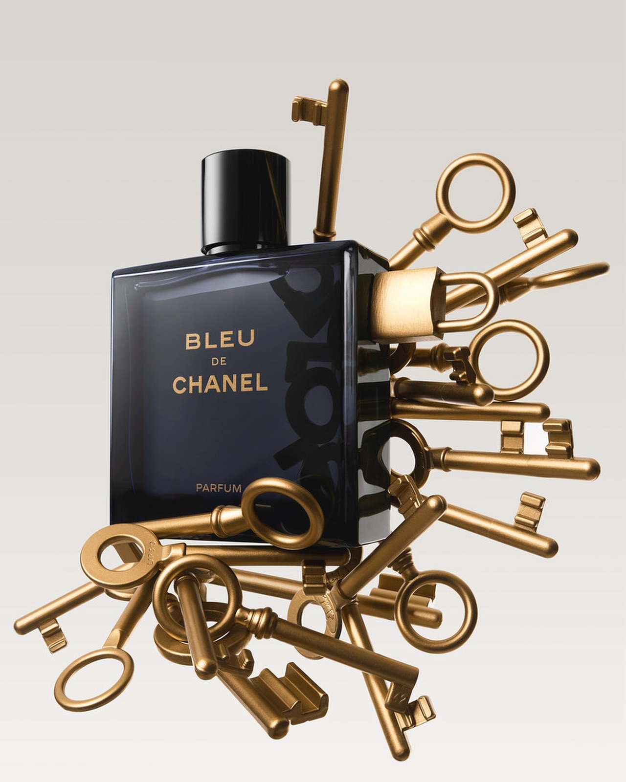 Elegant studio shot of a Bleu de Chanel parfum bottle surrounded by antique gold keys, creating a luxurious and mysterious still life.